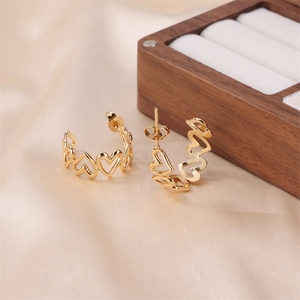 Detailed close-up of golden heart-shaped hoop earrings on elegant silk fabric