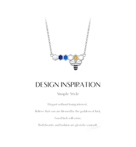 Macro detail of silver honeycomb pendant with blue enamel and colorful bee charm necklace