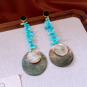 Detail of bohemian drop earrings with turquoise stones and iridescent round shell pieces