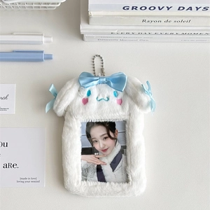 Close-up of white plush bunny photocard holder with a blue satin bow and metal chain