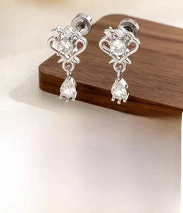 Detail of silver crown earring with hollow heart design and pear-shaped zircon pendant