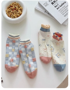 Detailed view of floral ankle socks with heart patterns and ruffle cuffs on a white desk