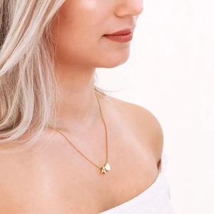 Collana dorata con ciondolo lettera A e piccolo cuore su modella con pelle naturale