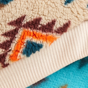 Close-up of soft sherpa fleece pet sweater fabric with colorful geometric totem patterns