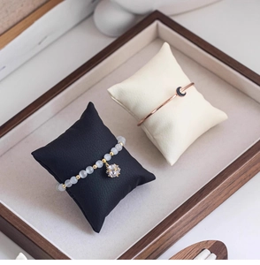 Macro shot of beaded bracelet and rose gold bangle on display pillows in a tray