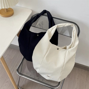 Détail de sacs fourre-tout en noir et crème avec une texture côtelée verticale chic