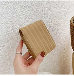 Detail showing beige mini cosmetic bag with vertical wave texture and built-in mirror