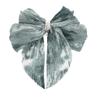 Close-up of tie-dye green chiffon bow hair clip with triple row pearl center detail