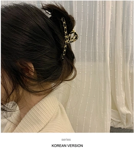 Close-up of elegant gold and black ribbon-wrapped hair claw clip worn by a model