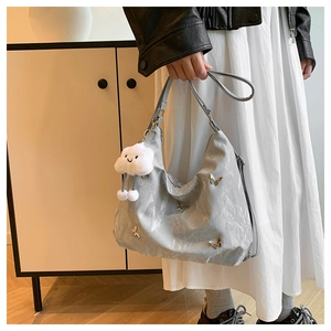 Detail of silver pleated bag featuring metal butterfly and white plush cloud pendant