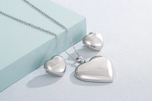Polished silver heart jewelry set with necklace and earrings on geometric display