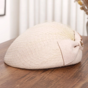 Close-up of beige wool beret featuring elegant mesh veil and bow detail in retro style