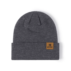 Front view of heather grey knit beanie featuring a brown faux leather M patch on white background