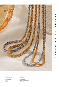 Detailed shot of gold and silver braided chain necklaces on fabric with amber glassware