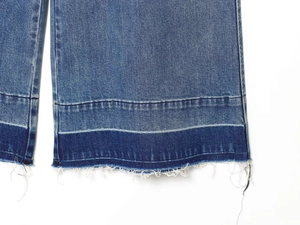 Detailed close-up of blue high-waisted wide-leg jeans with frayed hem and contrast panels