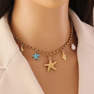 Gros plan d'un collier doré avec breloques d'étoile de mer et perles sur un mannequin
