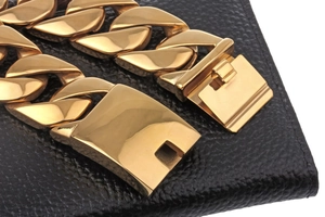 Close-up of a 18k gold plated Cuban link bracelet with a polished clasp on black background