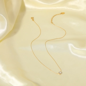 Minimalist gold necklace with six-prong zircon pendant on elegant beige silk fabric