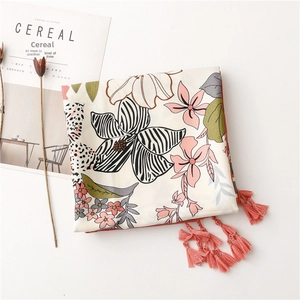 Detail of floral printed scarf with pink fringe tassels and elegant botanical pattern