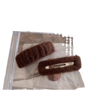 Brown fuzzy hair clip set with ribbed texture displayed on a transparent stand