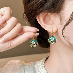 Close-up of vintage flower earrings with green enamel and pearls on a female model