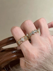 Detail of gold clover rings with zircon stones shown on a warm luxury background