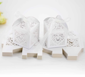 Detailed laser-cut white wedding favor box with heart pattern and white ribbon tie