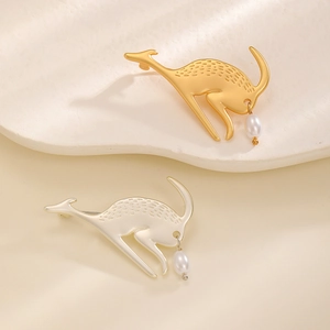 Vue détaillée de broches cerf dorée et argentée avec perles pendantes sur plateau céramique