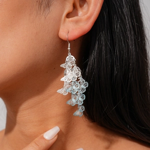 Close-up of layered hollow butterfly tassel earrings with blue gradient on a female model