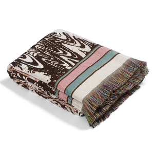 Detail of bohemian knit outdoor blanket with swirl pattern and colorful tassels
