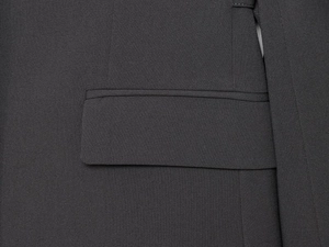 Detailed close-up of a classic flap pocket on a dark grey tailored suit jacket