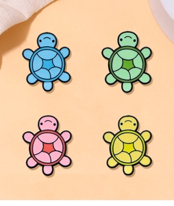 Set of four colorful cartoon turtle badges in blue, green, pink and yellow enamel finish