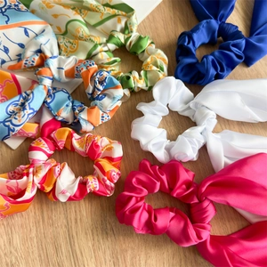 Flat lay of colorful silk bow scrunchies with long ribbons on a light wood background