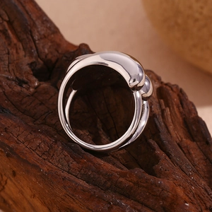 Macro shot of silver metal ring with organic water drop curves on textured dark wood