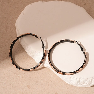 Macro shot of large hoop earrings with leopard print leather texture on display stone