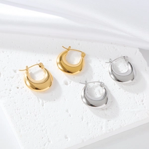 Close-up of gold and silver teardrop earrings on a textured stone and silk surface