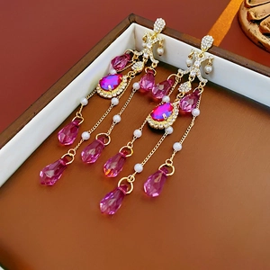 Close-up of pink crystal tassel earrings with gold plating and pearls in a leather box
