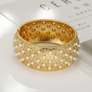 Vintage wide gold alloy bangle featuring geometric relief and white faux pearl inlay