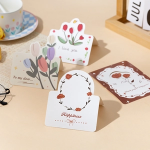 Close-up of floral greeting cards with tulip and rose illustrations on a beige desk