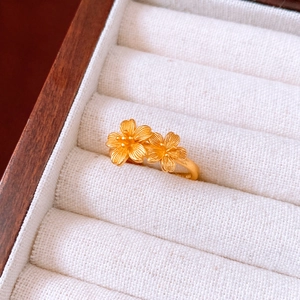 Macro shot of gold-plated cherry blossom ring with matte texture in a white jewelry box