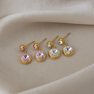 Vue macro de boucles d'oreilles en acier doré avec cristaux roses et transparents