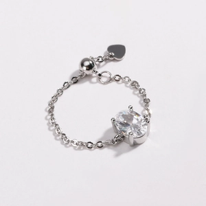 Detail of silver chain ring with oval zircon, heart pendant and adjustable ball slide