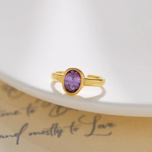 Detail of oval purple crystal ring in gold finish on vintage paper background