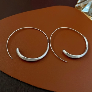 Macro shot of silver minimalist geometric hoop earring on a premium brown leather texture
