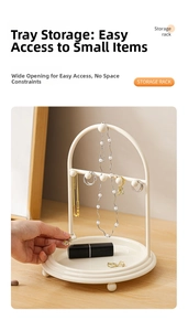 Cream jewelry organizer rack with metal hooks and a tray on a wooden desk