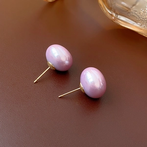Macro shot of purple pearl earrings with gold pins on brown leather background