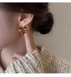 Close-up of vintage tiger eye beaded hoop earring worn by a model in warm Maillard style