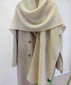Detailed view of cream white thick knit scarf texture on a beige cashmere coat