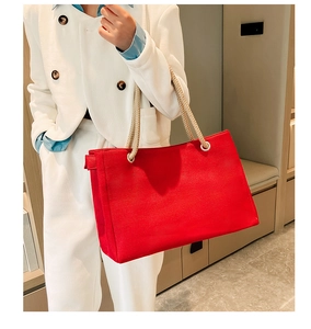Detail of red canvas tote bag featuring thick rope handles and durable woven texture