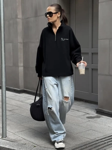 Detail of black half-zip sweatshirt featuring white letter print and high-quality fabric